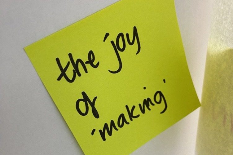 Yellow sticky note on white background with handwriting: The joy of making