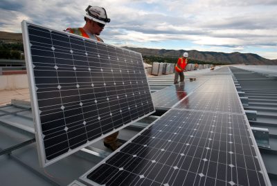 Installing photovoltaic panels on the roof at the Research Support Facility (RSF). NREL works on panels that DOE is using leverage a Power Purchase Agreement with SunEdison and Xcel Energy to absorb the upfront installation costs. Original public domain image from Flickr